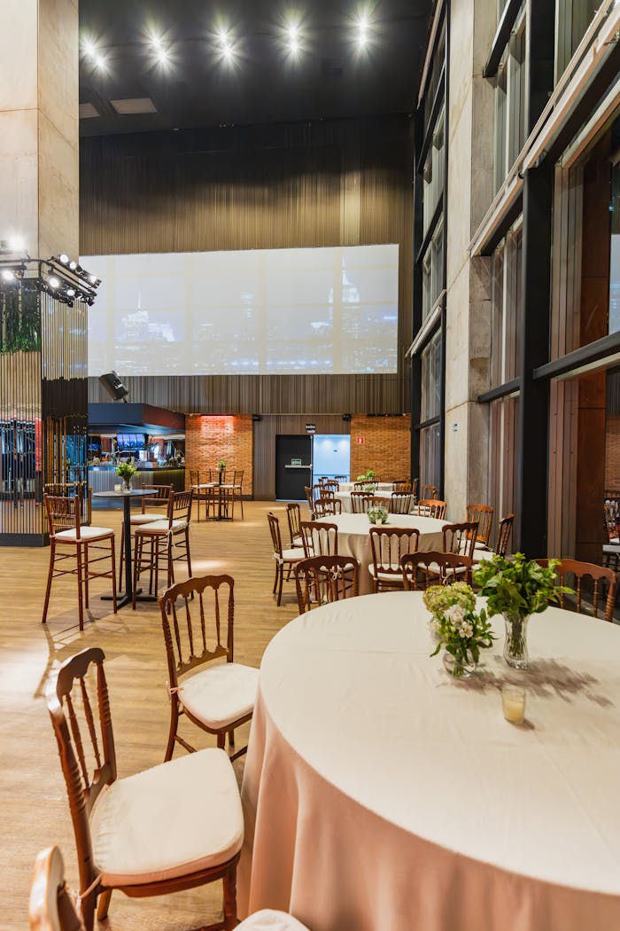 Spacious banquet hall with round tables and floral decor, ideal for celebrations or gatherings.